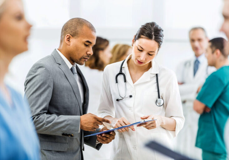 Doctor collaborating with a businessman. Young female doctor and African American businessman working together.